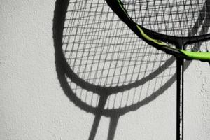 der schatten von badmintonschlägern auf weißer wand, weicher und selektiver fokus, konzept für badmintonsportliebhaber auf der ganzen welt. foto