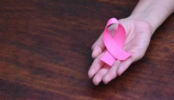 rosa Schleife in der Hand, ein Symbol der weltweiten Brustkrebskampagne für Frauen. foto