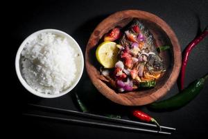 würziges gebratenes Fischmenü mit Reisschüssel auf schwarzem Hintergrund. asiatische Lebensmittelfotografie. gut für Speisekarte und Poster foto
