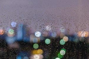 Regentropfen auf Fenster mit bunten Bokeh-Lichtern. foto