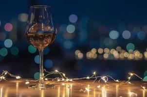 ein glas roséwein mit buntem stadt-bokeh-lichthintergrund.