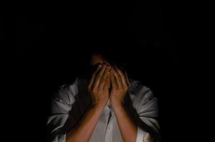 Elend depressiver Mann, der allein im dunklen Hintergrund sitzt. Konzept für Depressionen und psychische Gesundheit. foto