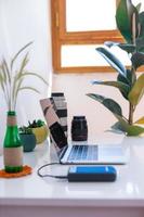 Arbeitsplatz, Laptop und Kameraobjektive des Fotografen auf einem weißen Tisch foto