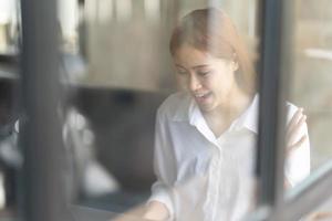 Porträt einer selbstbewussten Geschäftsfrau am Arbeitsplatz, lächelnde Mitarbeiterin, die hinter einem Laptop sitzt. foto