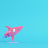 rosafarbene Rakete mit Ständer auf hellblauem Hintergrund in Pastellfarben. Minimalismus-Konzept foto