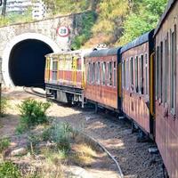 Spielzeugeisenbahn, die sich auf Berghängen bewegt, schöne Aussicht, ein Seitenberg, ein Seitental, das sich auf der Eisenbahn zum Hügel bewegt, inmitten grüner Naturwälder. Spielzeugeisenbahn von Kalka nach Shimla in Indien foto