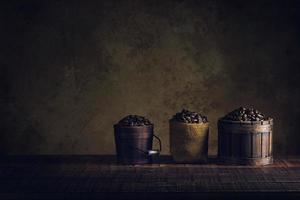 Kaffeebohnen im Behälter auf Holzfußboden und altem Papier im Alter von Hintergrund oder Textur