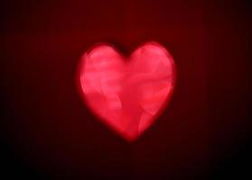 rote unscharfe Herzform aus leichtem Bokeh auf schwarzem Hintergrund foto