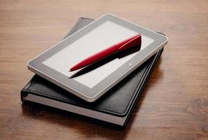 Tablet-Gerät auf Notebook am Holztisch foto