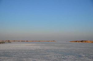 zugefrorener See und Hütten mit Schilf foto