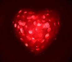 rote unscharfe Herzform aus leichtem Bokeh auf schwarzem Hintergrund foto