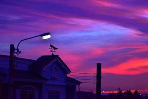Wetterfahne bei Sonnenaufgang mit leuchtenden Farben in den Wolken foto