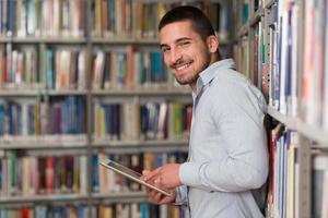 junger Student mit seinem Laptop in einer Bibliothek foto