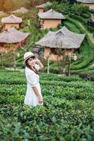 glückliche touristenfrau im weißen kleid genießen schönen teegarten. reisenderbesuch im thailändischen dorf ban rak, mae hong son, thailand. Reise-, Urlaubs- und Urlaubskonzept foto