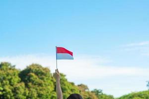 Hand, die Indonesien-Flagge auf Hintergrund des blauen Himmels hält. indonesischer unabhängigkeitstag, nationalfeiertag und fröhliche feierkonzepte foto