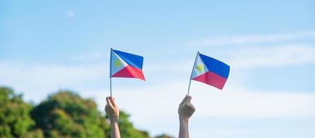 Hand, die Philippinen-Flagge auf Naturhintergrund hält. 12. juni des unabhängigkeitstages und fröhliche feierkonzepte foto