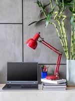 moderner Schreibtisch mit Laptop, Lampe und Blumenvase foto