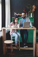 modernes Team arbeitet im Café mit Laptop, Smartphone mit Kaffee