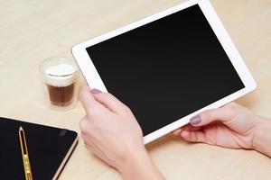 Mädchen, das eine digitale Tablette mit einem Kaffee betrachtet foto