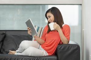 asiatische Frau zu Hause beim Lesen eines Tablet-PCs.