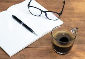 Tasse Kaffee auf einem Holztisch mit Notizbuch und Stift foto