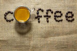 Draufsicht auf eine Tasse schwarzen Espressokaffee mit einer schönen Crema auf Sackleinen und brauner Arabica-Kaffeebohne. natürliches Sonnenlicht, erfrischen Sie sich durch ein gutes Getränk mit Koffein foto