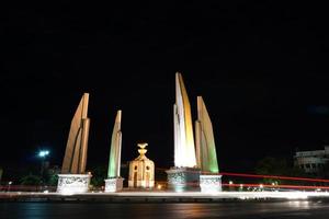 thailand demokratiedenkmal in der nacht mit bewegungsautolicht auf der straße. foto