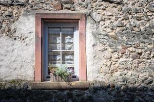 Ein altes Fenster an einer Wand mit einem Blumenkorb foto