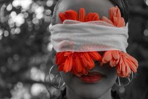 Frau mit roten Blumen, die um ihre Augen verbunden sind foto