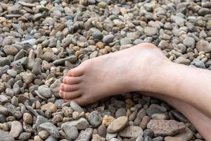 Teilansicht eines menschlichen nackten Fußes auf Kieselsteinen foto