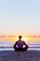 Mann meditiert am Strand foto