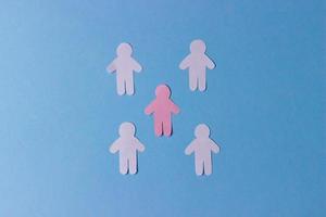 Menschen aus Papier ausgeschnitten. rosa Silhouette eines Mannes, umgeben von weißen Silhouetten. das konzept der kommunikation, teamarbeit, gesellschaft foto