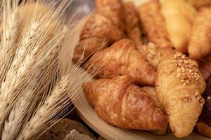 Croissant in Holzschale und Weizengras auf dem Tisch foto