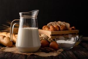 Milch in einem Krug auf einem Holztisch mit Zutaten foto