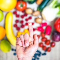 hand, die nahrungsergänzungsmittel über gemüse und obst für einen gesunden lebensstil hält foto