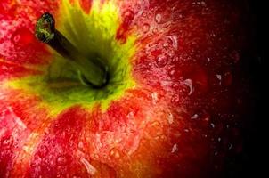Wassertropfen auf glänzender Oberfläche von rotem Apfel auf schwarzem Hintergrund foto