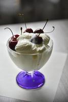 cremig-süßes Eis in einer Glas-Eismaschine mit großen Kirschbeeren foto