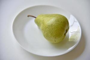 Grüne köstliche Birnen auf einer weißen Tellernahaufnahme foto