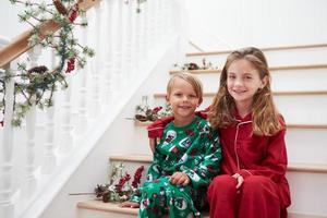 zwei Kinder sitzen auf Treppen im Pyjama zu Weihnachten foto