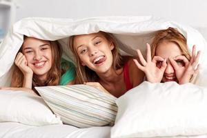 glückliche junge Frauen im Bett zu Hause Pyjama-Party foto