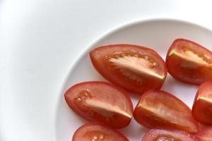 in Scheiben geschnittene rote Tomate auf einem weißen Teller foto