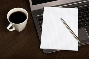 Notizbuch, Stift auf Laptop neben Tasse Kaffee. foto