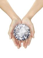 schöne Frauenhand, die einen schillernden Diamanten auf einem weißen, isolierten Hintergrund hält foto