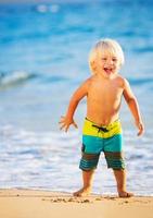 kleiner Junge, der am Strand spielt foto