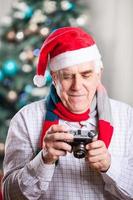 älterer Mann, der Foto auf Weihnachtshintergrund nimmt