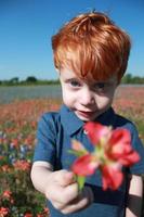 rothaariger Junge mit Blume foto