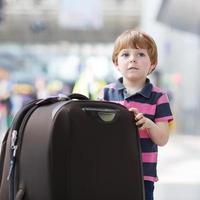 kleiner Junge auf Urlaubsreise mit Koffer am Flughafen