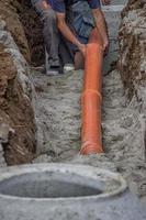 Arbeiter verlegen PVC-Rohre am Grabenboden 2