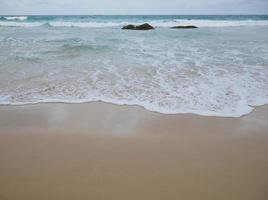 weiße Wellenspritzer am Sandstrand für Hintergrundbilder foto