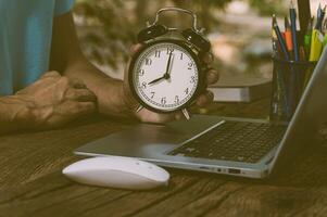 die hand, die die uhr hält, ist am arbeitstisch. foto